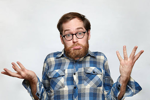 Confused bearded man in eyeglasses shrugging his shoulders